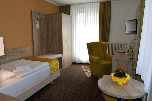 a hotel room with a bed and a chair and a table at Akzent Hotel Am Burgholz in Tabarz
