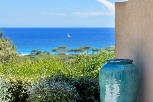 a blue vase sitting next to a wall next to the ocean at Les Bergeries De Palombaggia in Porto-Vecchio