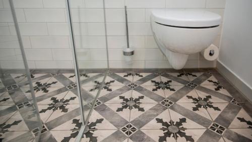 a bathroom with a toilet and a tiled floor at Griesbräu zu Murnau in Murnau am Staffelsee