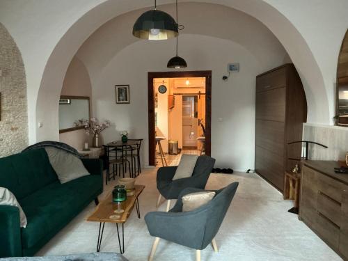 a living room with a green couch and chairs at Apartmány na Náměstí in Český Brod
