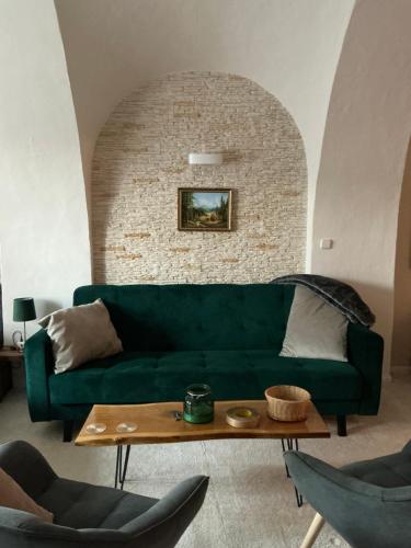 a living room with a green couch and a table at Apartmány na Náměstí in Český Brod