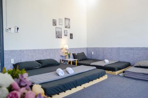 a room with three beds and a woman sitting on a table at La Jonquille Vũng Tàu in Vung Tau