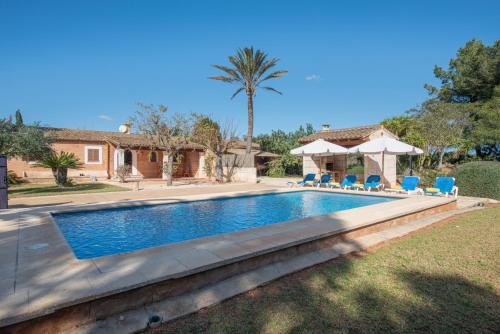 a swimming pool with chairs and a house at Es Ravellar - Campos in Islas Baleares