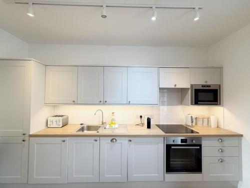 a white kitchen with white cabinets and a sink at Alma Vale Apartments 4 - Hopewell in Bristol