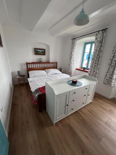 a bedroom with a white bed and a table at Chalupa v pohádce in Nový Rychnov