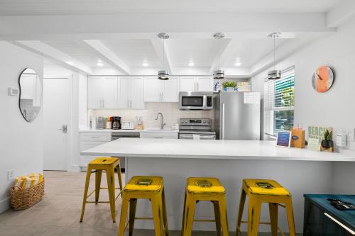 a kitchen with three yellow stools and a counter at Bayview Inn #101 in Bradenton Beach