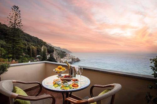 a table on a balcony with a view of the ocean at Anantara Convento di Amalfi Grand Hotel in Amalfi