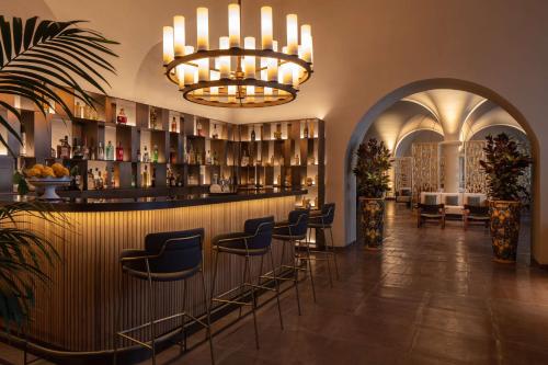 a lobby with a bar with chairs and a chandelier at Anantara Convento di Amalfi Grand Hotel in Amalfi