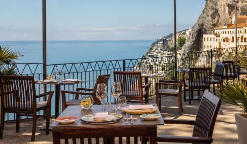 a table and chairs on a balcony with a view of the ocean at Anantara Convento di Amalfi Grand Hotel in Amalfi