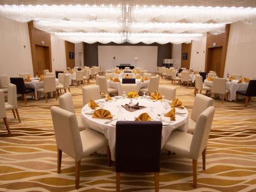 a large banquet hall with white tables and chairs at Novotel Jazan in Jazan