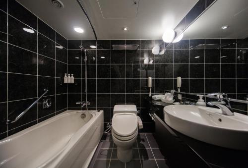 a bathroom with a tub and a toilet and a sink at ANA Crowne Plaza Matsuyama by IHG in Matsuyama