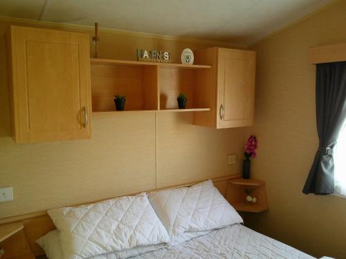 a bedroom with a bed and wooden cabinets at Highfields Rio 6 berth blow heated in Skegness