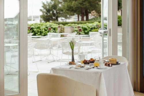 a white table with plates of food on it at Tivoli Portopiccolo Sistiana Wellness Resort & Spa in Sistiana