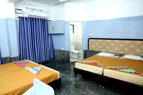 a room with two beds and a toilet in it at Sauhrudam Resort and Restaurant-Kanyakumari in Kanyakumari
