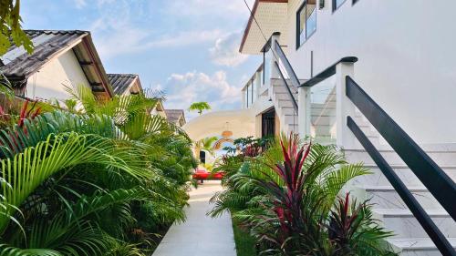 a pathway leading to a house with plants at The White House Beach Apartments Koh Phangan in Ban Nua