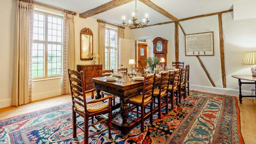 a dining room with a table and chairs on a rug at Chalford Manor in Aston Rowant