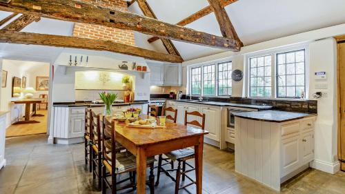 a kitchen with white cabinets and a wooden table at Chalford Manor in Aston Rowant