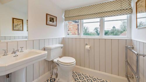 a bathroom with a toilet and a sink and a window at Chalford Manor in Aston Rowant
