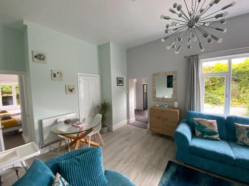 a living room with blue furniture and a chandelier at Little Dusty - Between St Agnes & Perranporth in St. Agnes