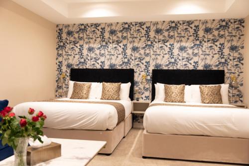 two beds in a room with floral wallpaper at Reem Hotel in London