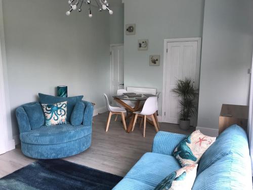 a living room with a blue couch and a table at Little Dusty - Between St Agnes & Perranporth in St. Agnes