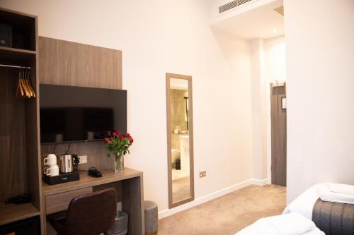 a living room with a television and a mirror at Reem Hotel in London
