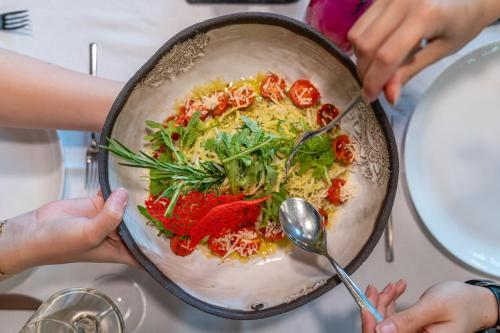 a person holding a dish of food with a spoon at Hotel Salzburger Hof Leogang in Leogang