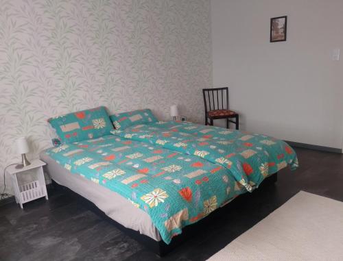 a bedroom with a bed with a blue comforter and a chair at Ferienwohnung Marie in Nohfelden