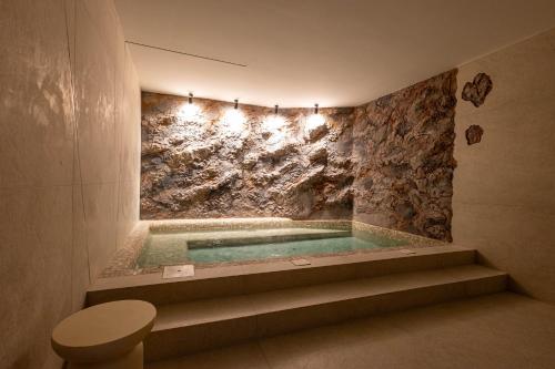 a bathroom with a tub with a stone wall at Olea Luxury Rooms & Spa in Split