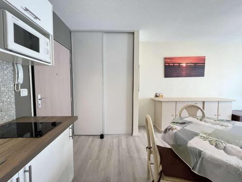 une chambre avec un lit et une cuisine avec un four micro-ondes dans l'établissement Appt Studio LA ROCHELLE - LR110-D107, à La Rochelle