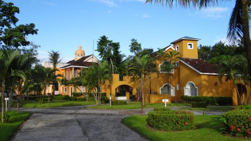 a yellow house with palm trees and a street at Amatique Bay Hotel in Puerto Barrios