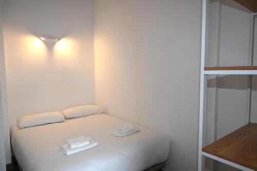 a small room with a white bed with two towels at Homenfun Dalt Badalona in Badalona