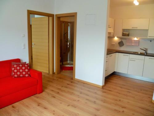 a living room with a red couch and a kitchen at Fröhlichhof Wohnung Pergola in Lagundo