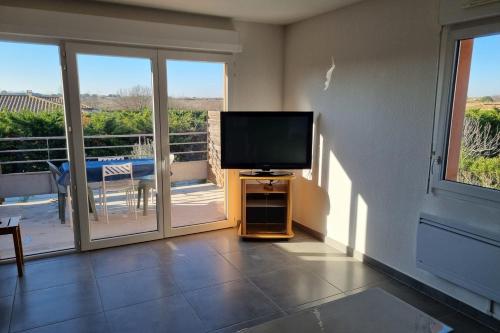Il comprend un salon doté d'une télévision à écran plat et d'un balcon. dans l'établissement Appartment 2 Bedrooms 60m - 4 people - Marseillan City, à Marseillan