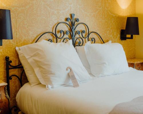 a bed with white pillows and a sign on it at Hotel Le Grimaldi by Happyculture in Nice