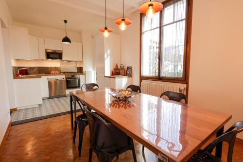 une cuisine et une salle à manger avec une table et des chaises en bois dans l'établissement Chez Roger - Maison Annecy, à Annecy