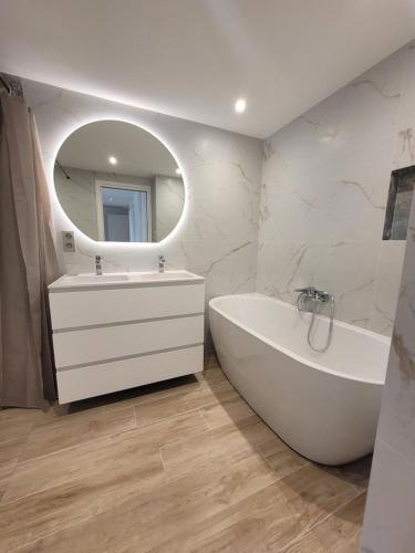 une salle de bain avec une baignoire, un lavabo et un miroir dans l'établissement Le Bijou de Valrose - 4 Bedroom with Pool, à Nice