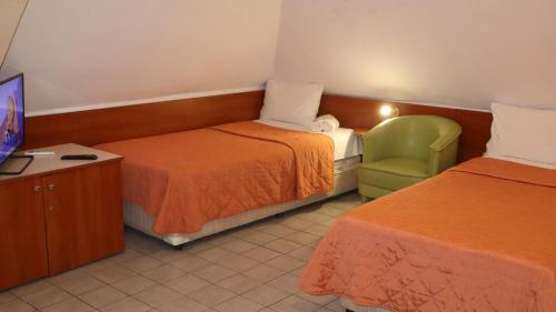 a hotel room with two beds and a green chair at Hotel Palitra in Varna City