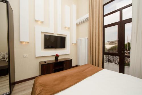 a bedroom with a bed and a tv and a window at Passage Hotel in Baku
