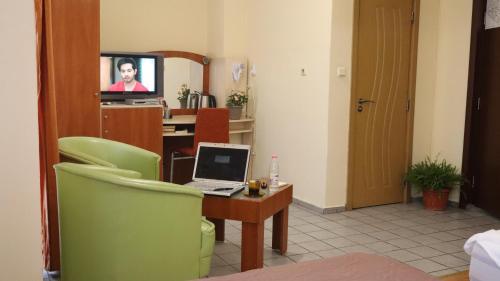 a room with a desk with a laptop and a television at Hotel Palitra in Varna City
