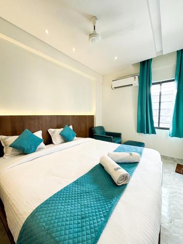 a bedroom with two beds with blue curtains at Hotel Emerald in Visakhapatnam