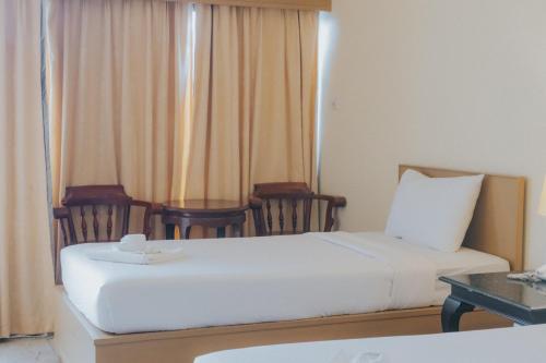 a hotel room with two beds and two chairs at Nonthaburi Palace Hotel in Nonthaburi