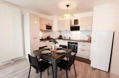 une cuisine avec une table et des chaises dans une pièce dans l'établissement Appartement 10 minutes Disneyland - parking gratuit, à Chessy