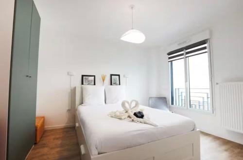 - une chambre dotée d'un lit blanc avec un animal rembourré dans l'établissement Appartement 10 minutes Disneyland - parking gratuit, à Chessy