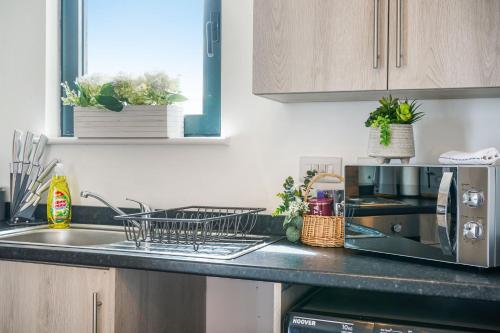 a kitchen counter with a dish rack on the sink at Affordable 1 & 2 Bed Apartments in Slough, Great Heathrow Location in Colnbrook
