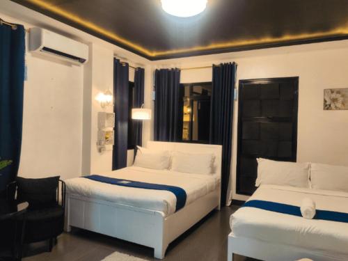 a bedroom with two beds and a chair at Gmb-Arte' Hotel in Sogod