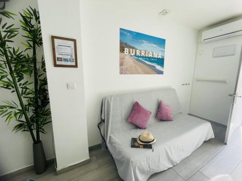 a room with a couch with pink pillows and a hat at Estudio Jimena Burriana en el centro de Nerja in Nerja