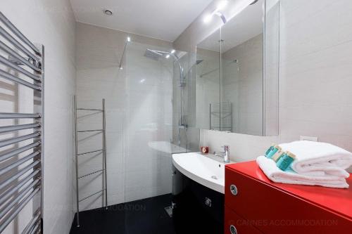 La salle de bains est pourvue d'un comptoir rouge avec un lavabo et un miroir. dans l'établissement Cruise, à Cannes