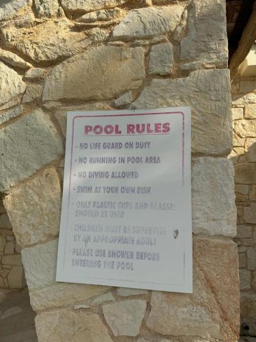 a sign on the side of a stone wall at Best Latchi Thalassa Villa in Lachi