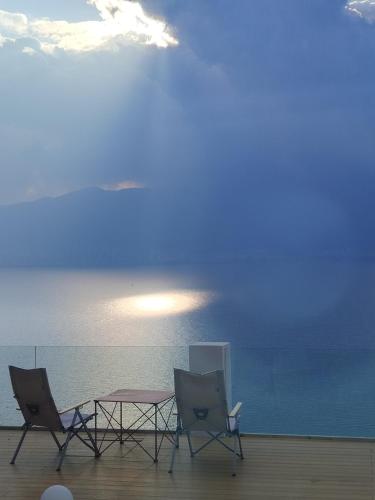 two chairs and a table on a balcony with the ocean at 大理麓屿悬崖海景民宿 in Dali